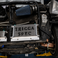Car engine with 'TRIGGA SPEC' oil cooler in a garage setting